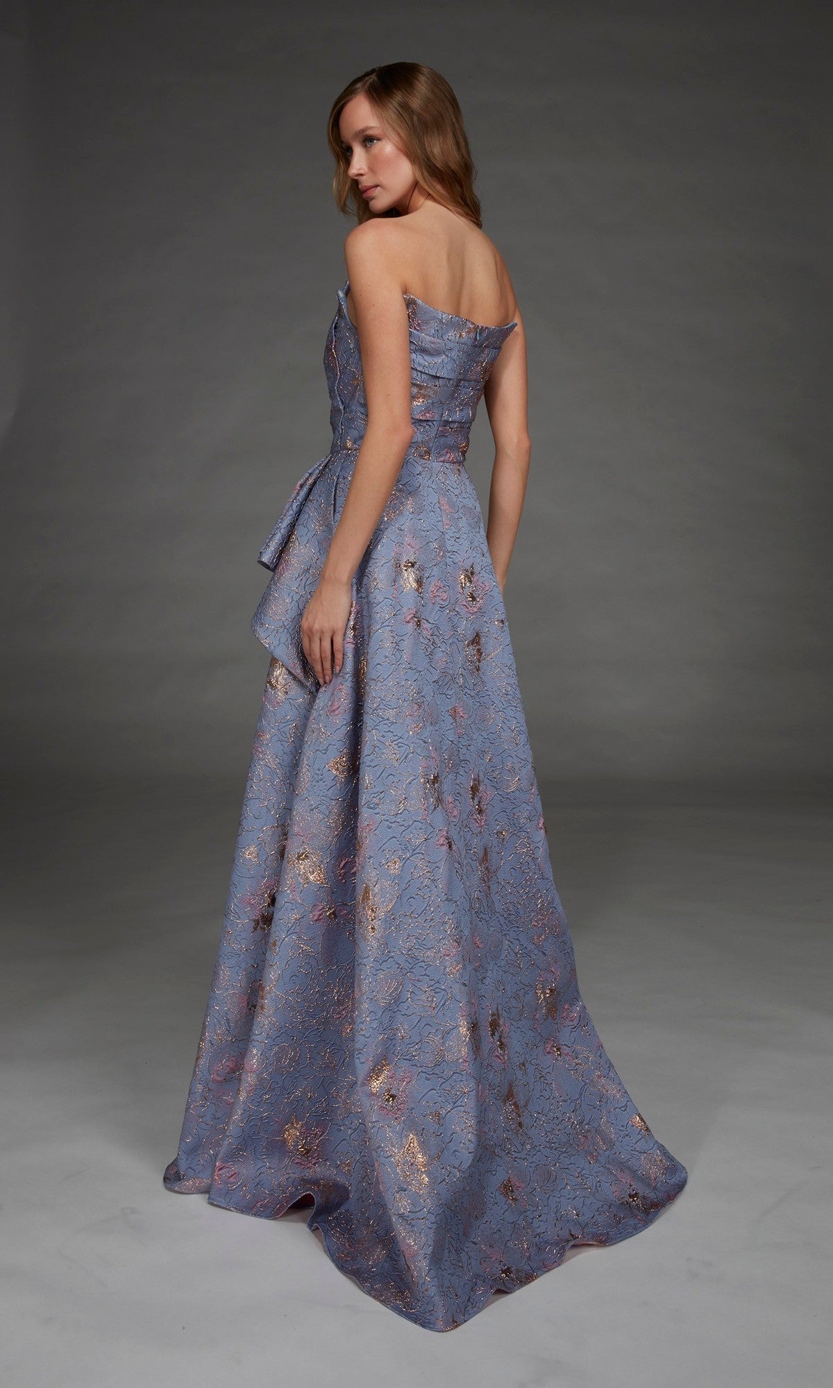 Wearing the Alyce 27893 Long Formal Dress, a floor-length, strapless gown featuring lavender jacquard fabric with metallic floral patterns, a woman poses elegantly in a studio.